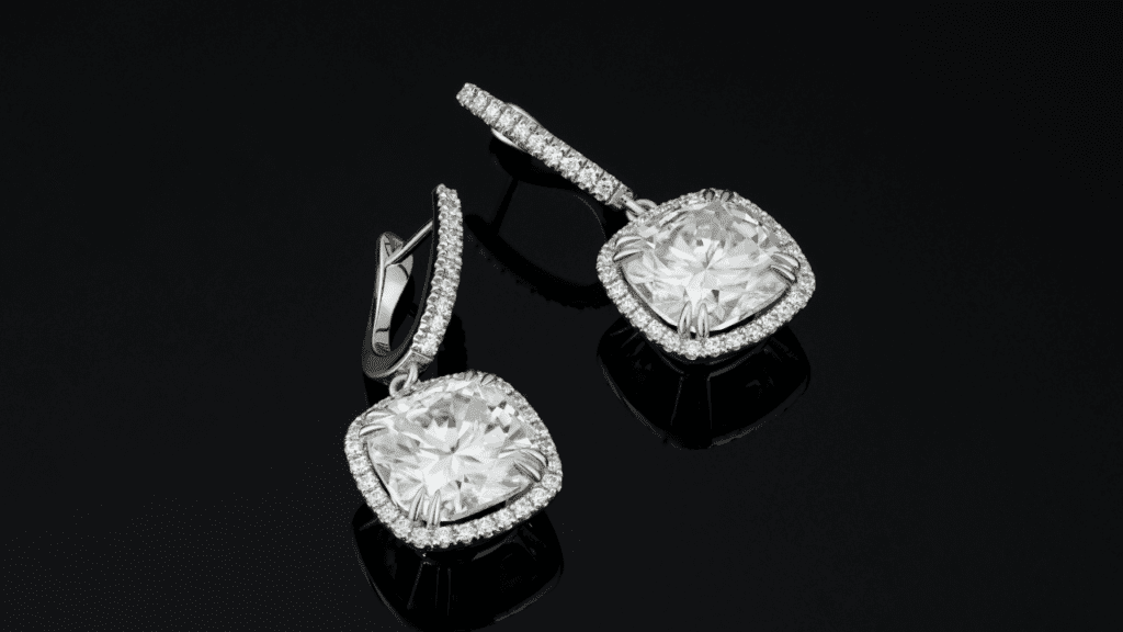 A pair of radiant drop earrings featuring large square-cut diamonds encircled by smaller diamonds, beautifully displayed on a reflective black surface.