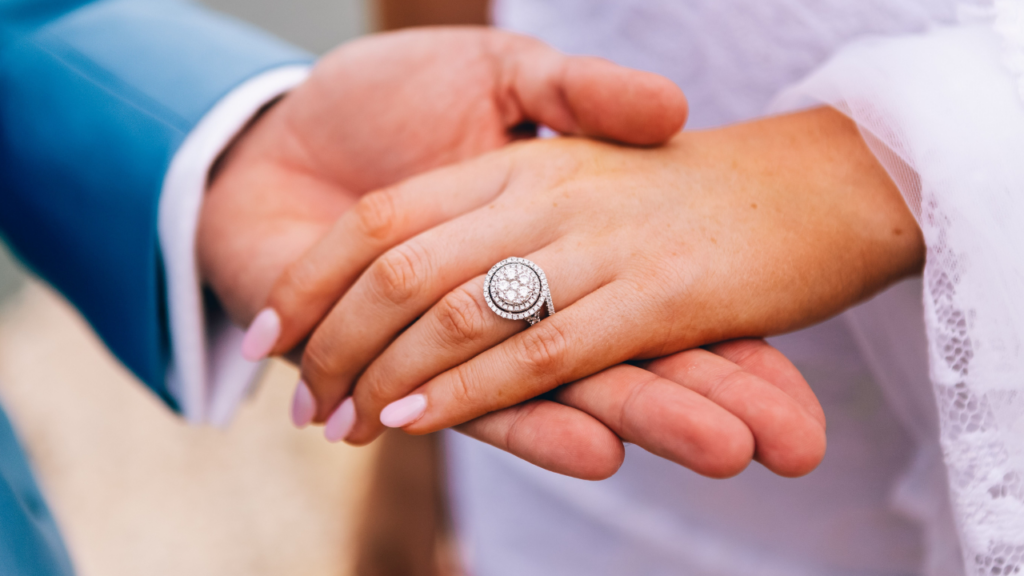 A close-up of newlyweds' hands, the bride's adorned with a large diamond, held together, capturing the essence of their union and commitment.