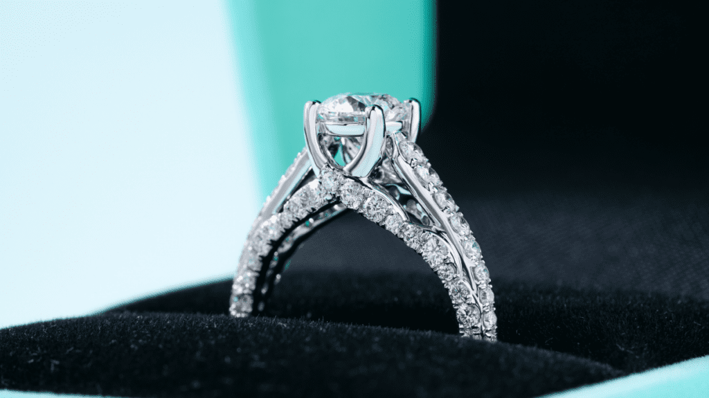 A stunning close-up of an intricately designed diamond engagement ring with a brilliant-cut central stone and pavé-set diamonds on a split shank band.