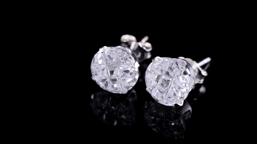 Close-up of two sparkling diamond stud earrings set in white gold, displayed against a sleek black background, showcasing their intricate design.