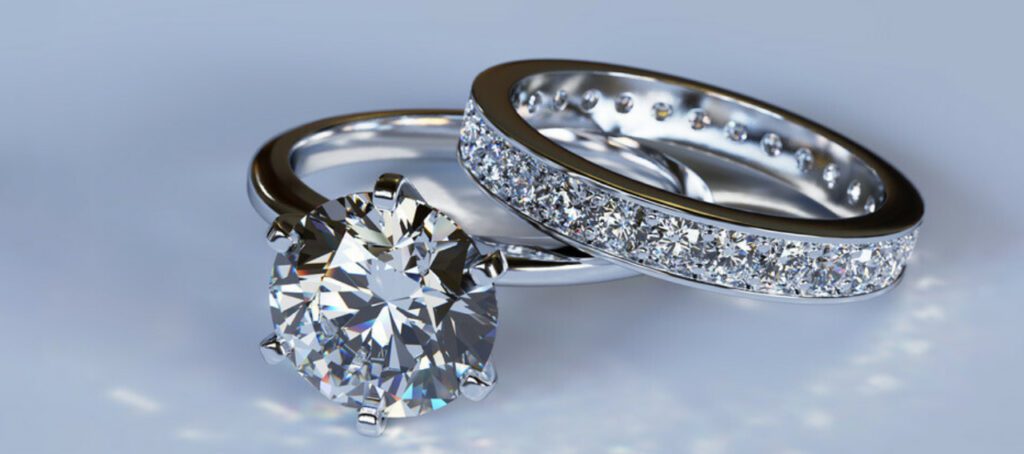 Two elegant silver rings: one featuring a large, brilliant-cut diamond solitaire, the other encrusted with a continuous row of smaller diamonds.