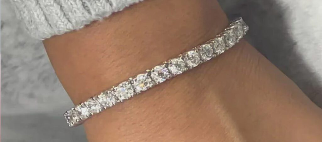 A close-up image of a wrist adorned with an elegant diamond tennis bracelet featuring a row of sparkling round-cut diamonds, creating a luxurious look.