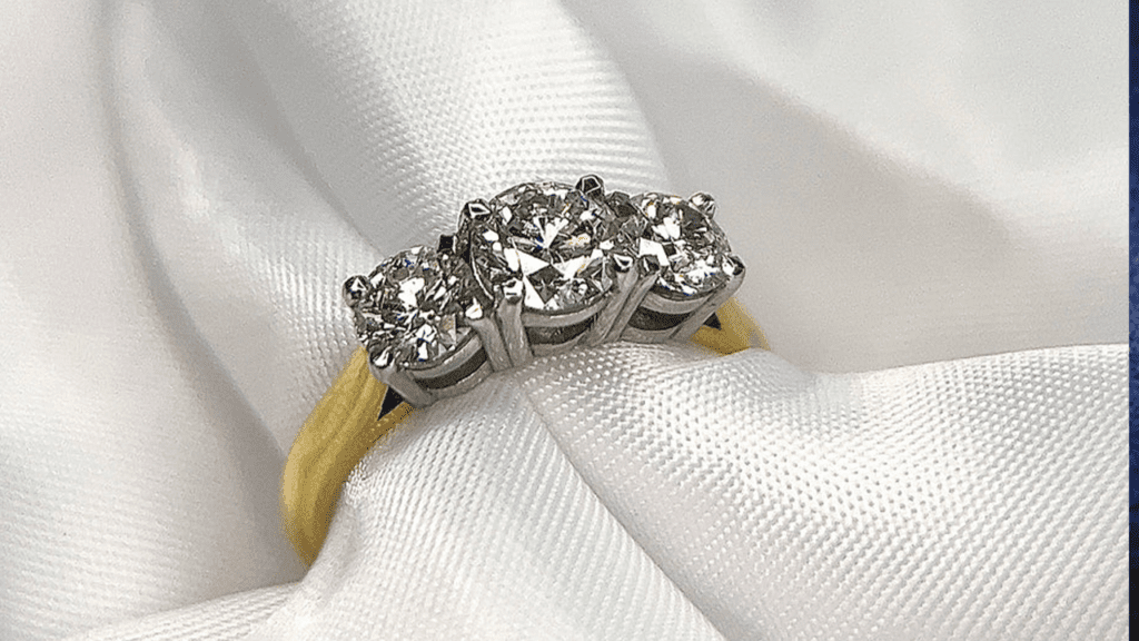 Elegant diamond engagement ring with a single sparkling stone on a soft white fabric. 