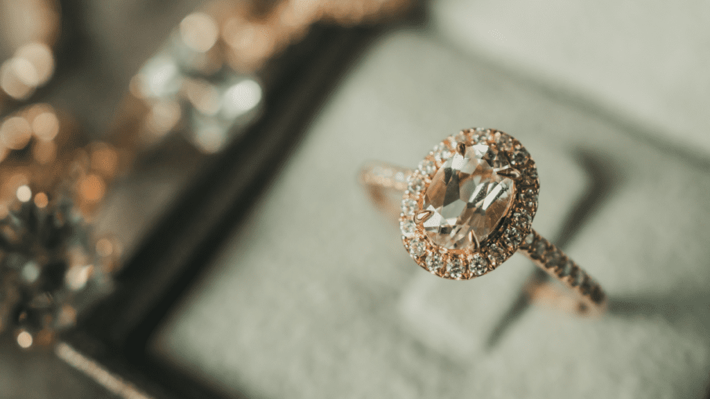A cushion-cut diamond ring in a velvet box, highlighting its brilliance and intricate setting against a soft, luxurious fabric background.