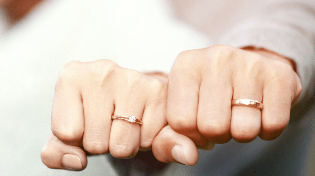 Interlaced hands with silver wedding bands, celebrating their enduring love.