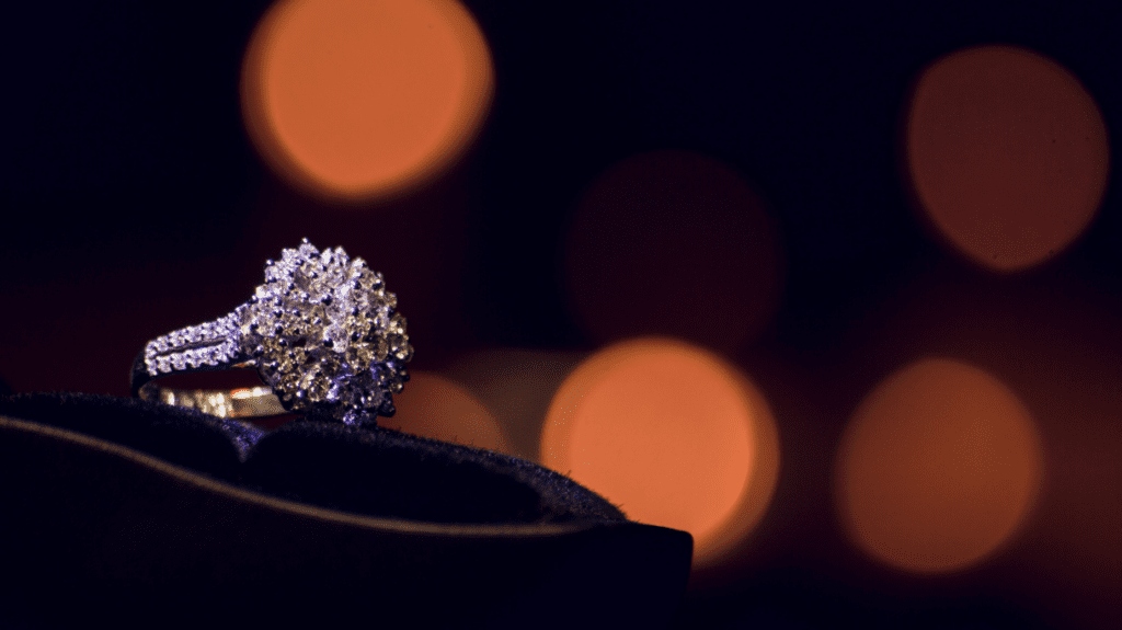 A breathtaking diamond cluster ring with a shimmering band, displayed against a backdrop of warm, bokeh lights, perfect for a romantic proposal.