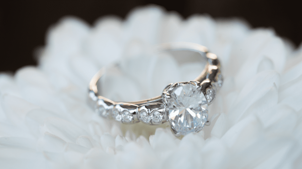 A pair of exquisite diamond rings, featuring a solitaire ring with a halo of smaller diamonds and a matching band encrusted with diamonds, on a marble surface.