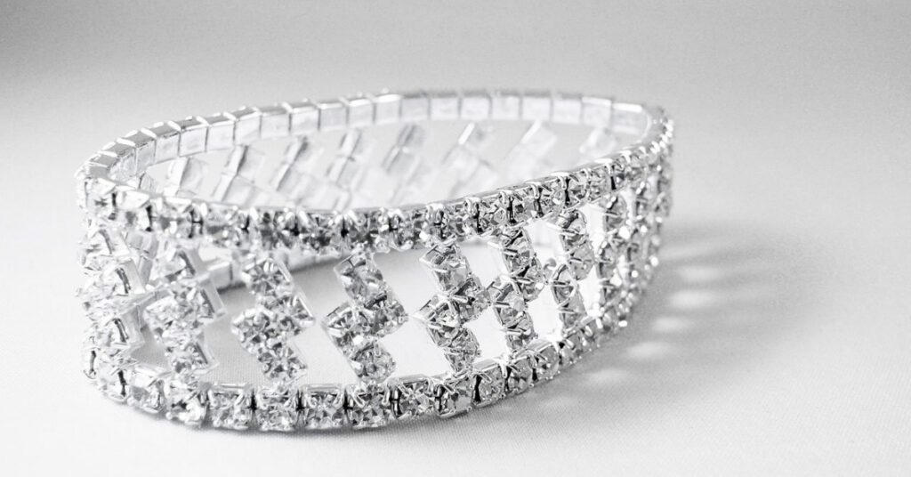 A sparkling, intricately designed diamond bracelet rests on a white surface, showcasing its elegant and luxurious craftsmanship.