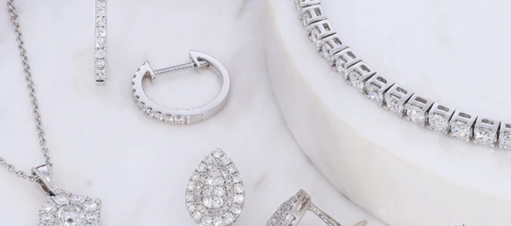 An array of sparkling diamond jewelry, including earrings, a necklace, and rings, elegantly displayed on a white surface, highlighting their brilliance.