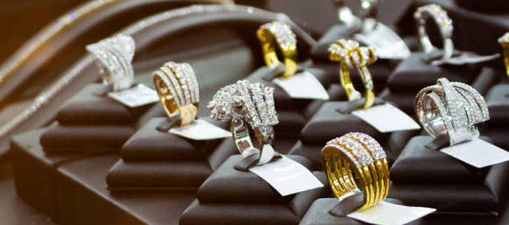 Display of luxury rings with gold and diamond embellishments showcased on black velvet stands under soft lighting in a high-end jewelry store.