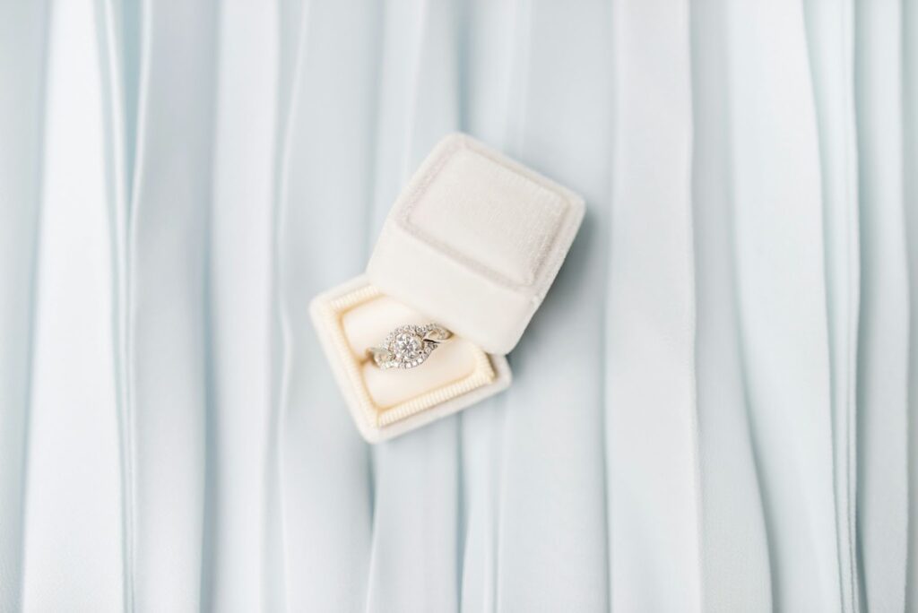 A delicate diamond ring nestled in a white velvet box, ready to be admired.