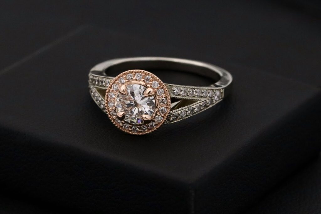 Stunning diamond engagement ring with rose gold halo and split shank, set against a sleek black background.