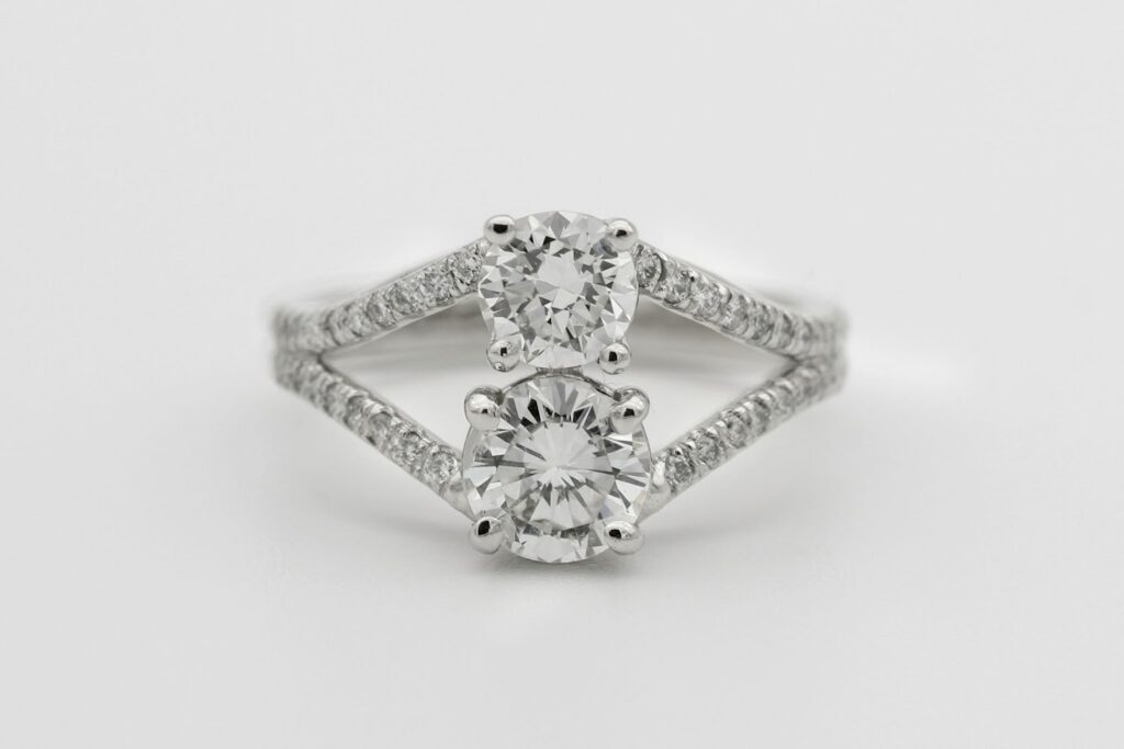 Stunning engagement ring featuring two brilliant round diamonds set in a split shank band adorned with pavé diamonds for added sparkle.