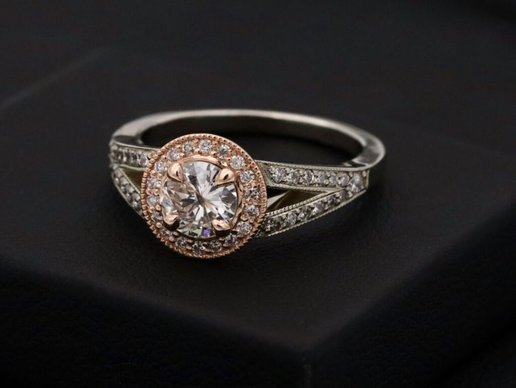 A close-up of a stunning diamond engagement ring with a halo setting, featuring a large central stone and smaller diamonds along the band, on black.