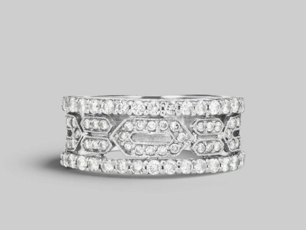 An intricate white gold band featuring geometric diamond patterns, bordered by rows of round-cut diamonds, showcasing a vintage-inspired design.