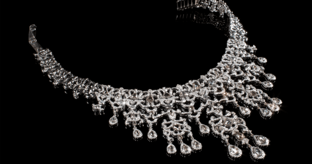 A stunning diamond choker necklace featuring intricate, cascading teardrop designs and sparkling accents throughout, set against a black background.