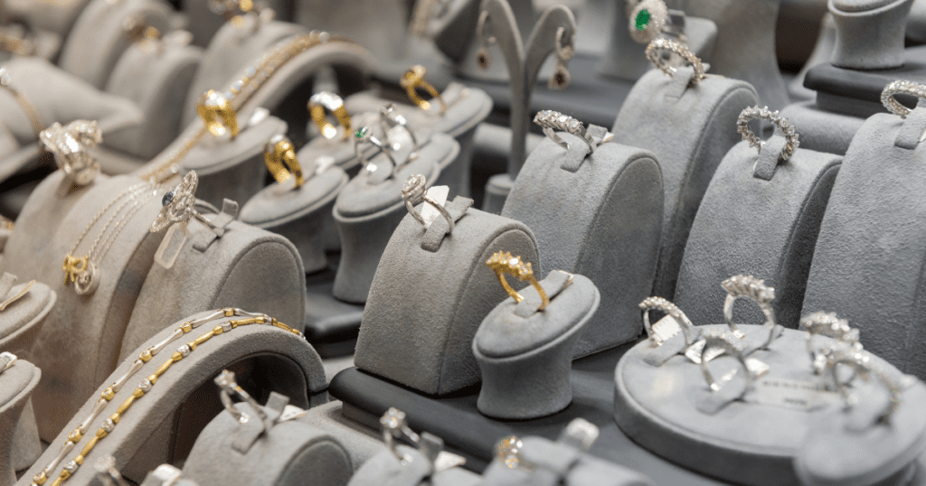 A diverse assortment of rings and bracelets elegantly displayed on grey velvet stands in a jewelry store, showcasing various designs and gemstones.