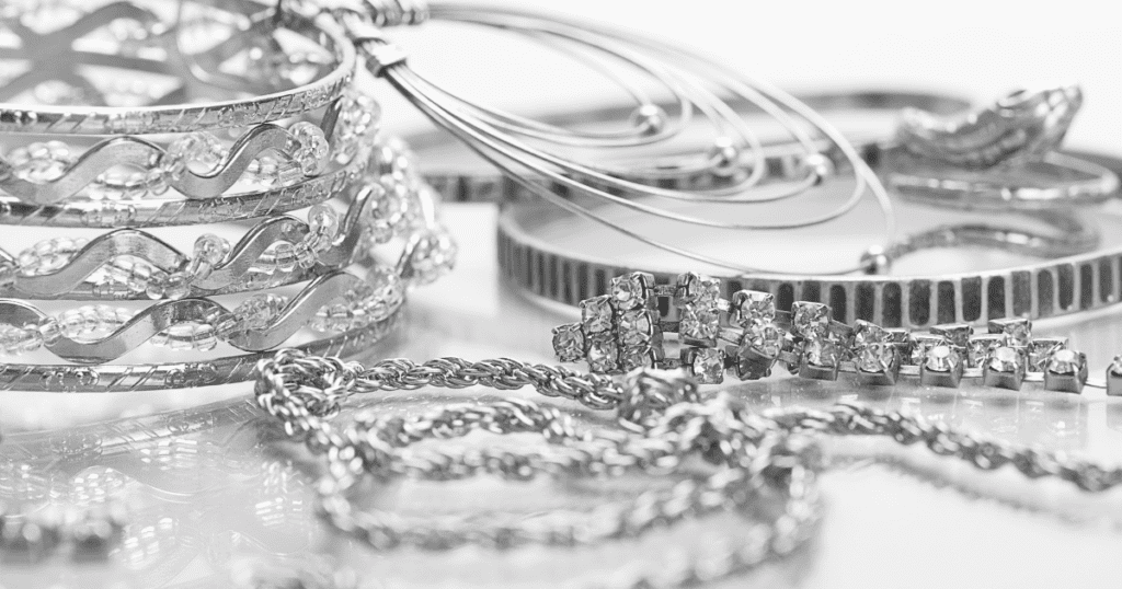 An elegant assortment of silver jewelry featuring intricately designed bangles, a woven chain, and sparkling diamond-studded pieces displayed together.