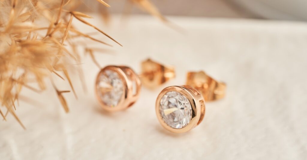 Elegant rose gold stud earrings featuring sparkling round-cut diamonds, set against a soft background with delicate dried floral accents.