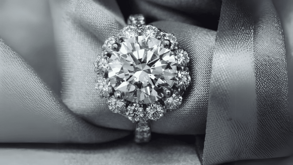  Dazzling diamond engagement ring with a halo setting, resting on a luxurious silver fabric.