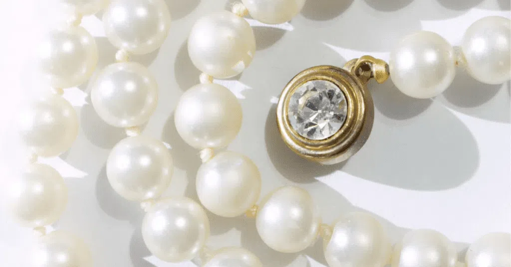 Classic pearl necklace with a gold-toned clasp and a sparkling rhinestone pendant.