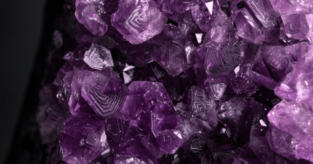 Intricate purple amethyst crystals with detailed geometric patterns, highlighting their natural beauty and unique formations against a dark backdrop.