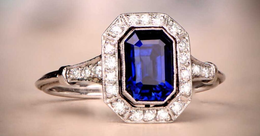 Stunning emerald-cut sapphire engagement ring with a diamond halo, set in platinum.