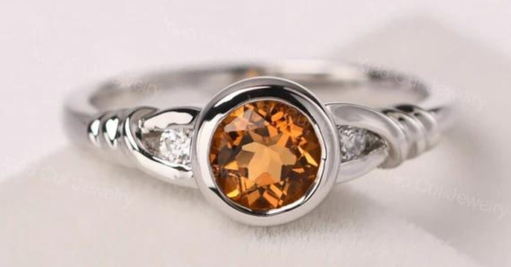 Elegant citrine ring with a twisted band and sparkling diamonds, set in white gold.