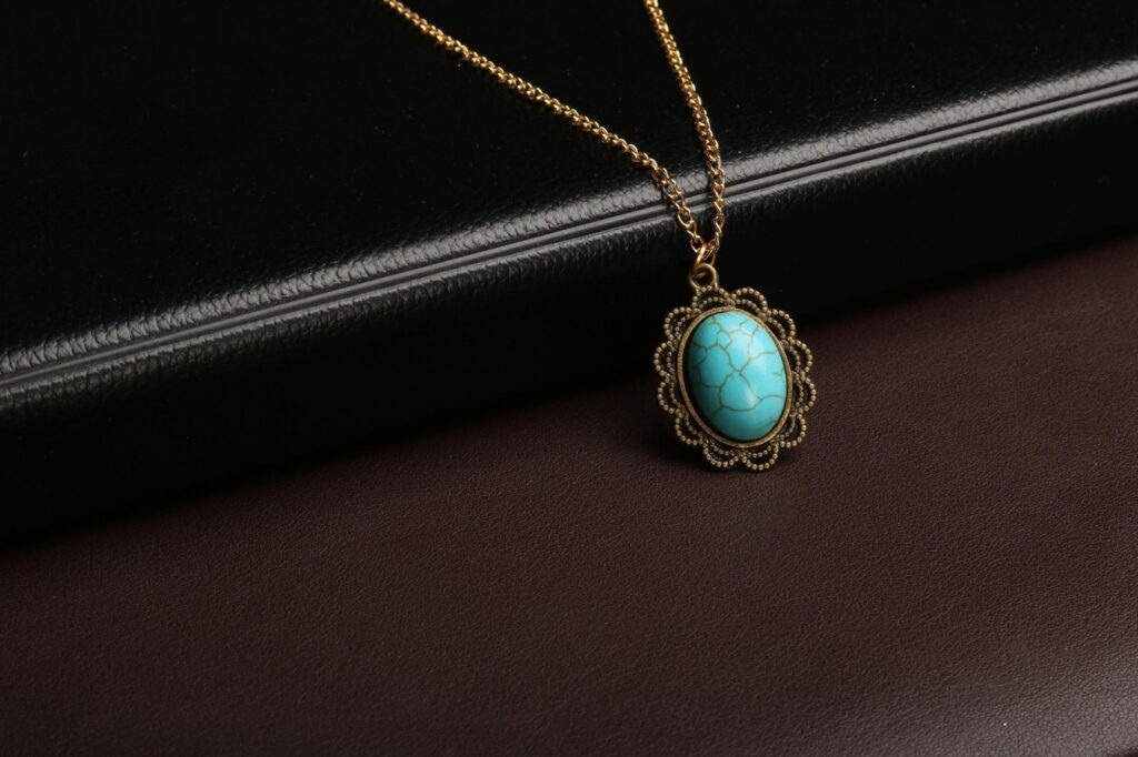 Vintage-inspired turquoise pendant necklace with a gold-toned chain and intricate filigree detailing.