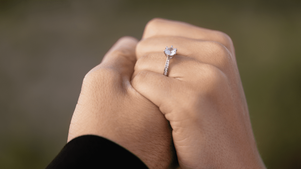 Romantic image of a couple holding hands, showcasing a beautiful diamond engagement ring on the woman's finger.