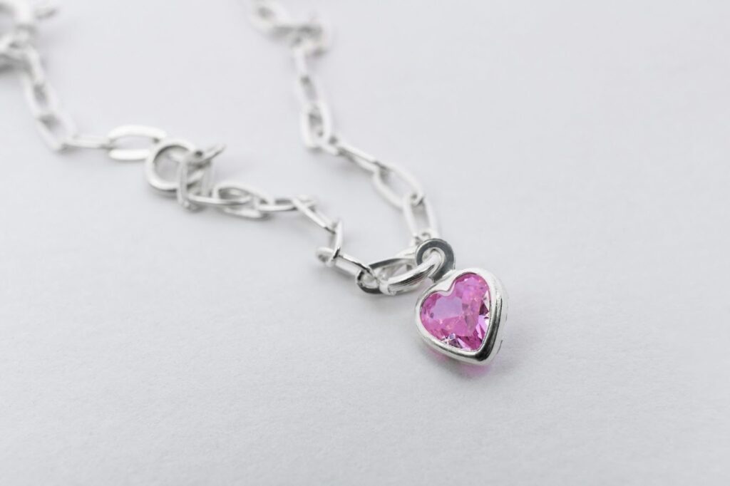 Delicate silver chain with a pink heart-shaped pendant.