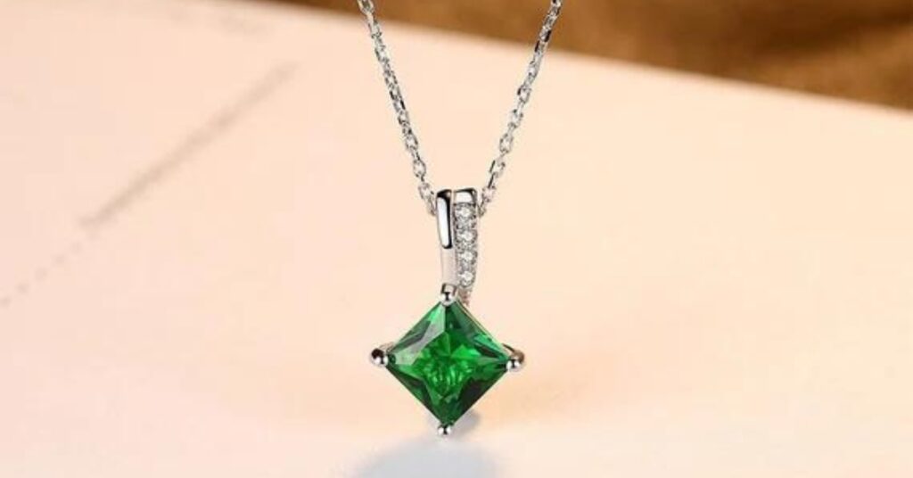 Stunning emerald-cut green gemstone pendant in a square shape, accented by a delicate silver chain with small diamonds, exuding timeless elegance.