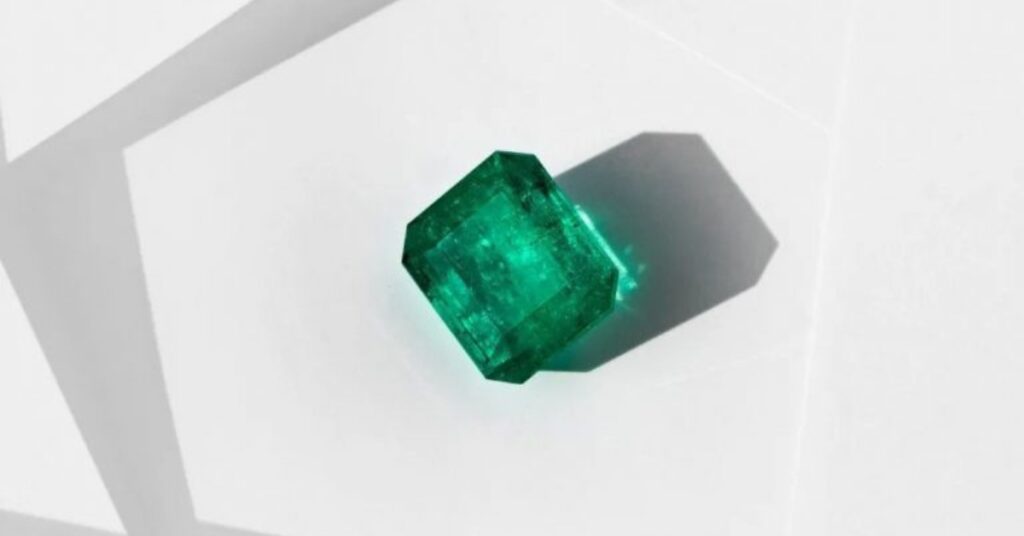 A vibrant green emerald gemstone with a square cut.