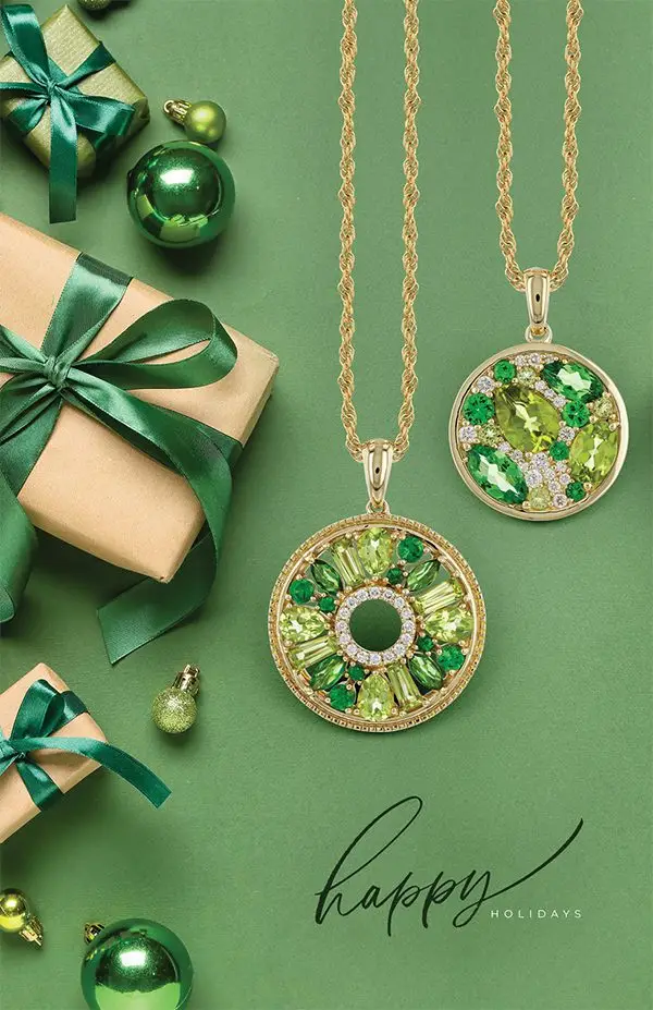 Two gold necklaces with green gemstone pendants, displayed on a festive green background with wrapped gifts, ornaments, and the message 'Happy Holidays.