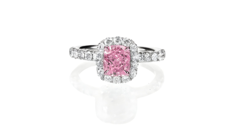 A pink diamond engagement ring with a halo of smaller diamonds on a white background.