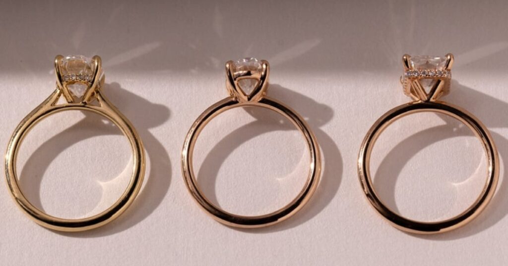 Three engagement rings with different colored gold bands: yellow, rose, and white gold, each with a round center stone and a halo setting.