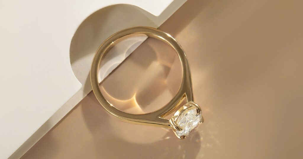 A classic solitaire engagement ring with a round-cut diamond set in a yellow gold band, displayed on a neutral background.