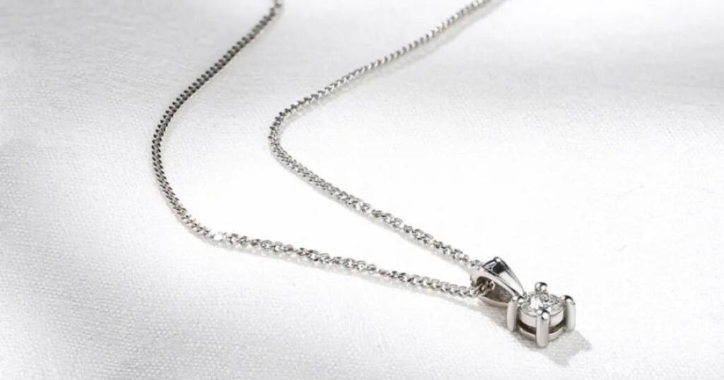 A delicate pendant necklace with a single diamond resting on a white background.