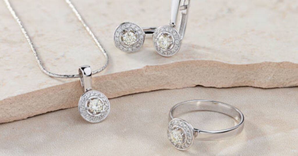 A set of elegant jewelry pieces: a ring, necklace, and earrings, all featuring round diamonds in a halo setting.