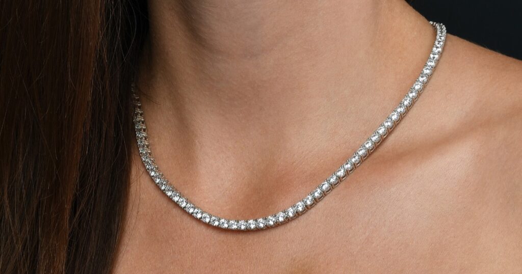 A close-up shot of a sparkling diamond tennis necklace worn around the neck, showcasing its elegant and seamless design with brilliant stones.