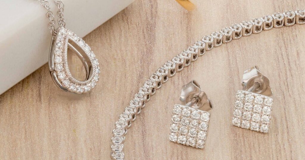 A stunning diamond jewelry set featuring a teardrop pendant necklace, a tennis bracelet, and a pair of square-cut stud earrings, all crafted in elegant white gold.