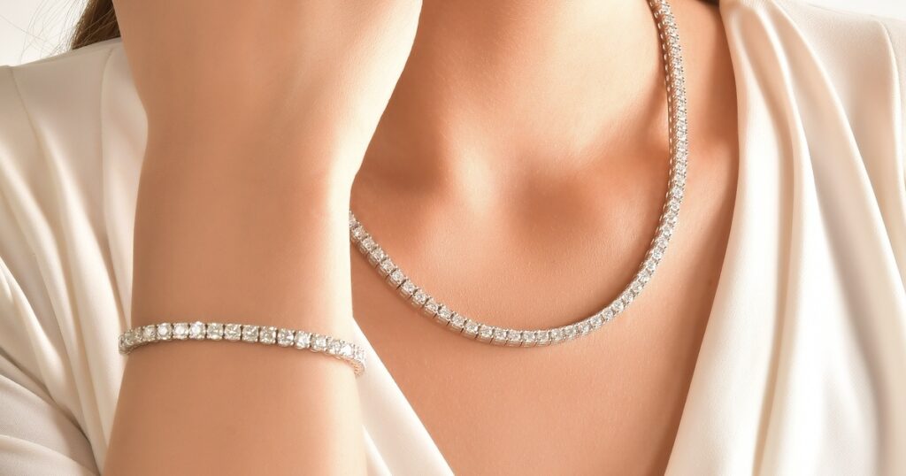 Close-up of a woman wearing an elegant diamond tennis necklace and matching bracelet, showcasing sparkling round diamonds set in a timeless white gold design.