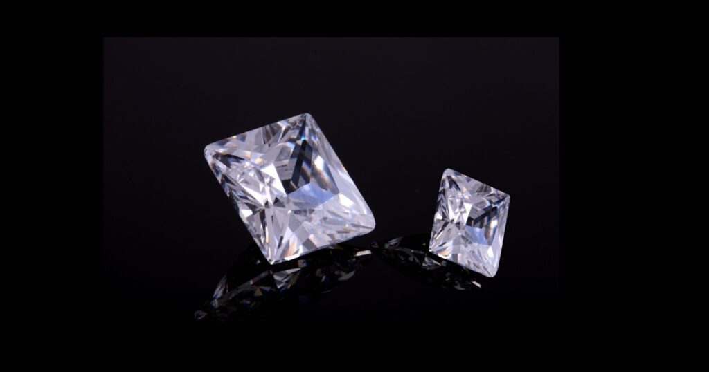 Two princess-cut diamonds of different sizes, sparkling on a black background.