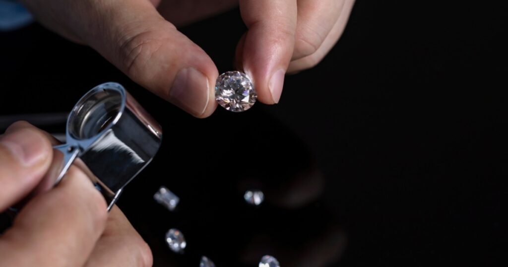 A jeweler inspecting a large, round diamond with a magnifying glass.