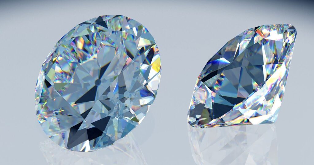 Two sparkling diamonds, one round and one oval-shaped, displayed on a reflective surface.