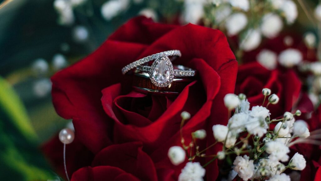 Wedding rings nestled in a vibrant red rose, symbolizing love and commitment.