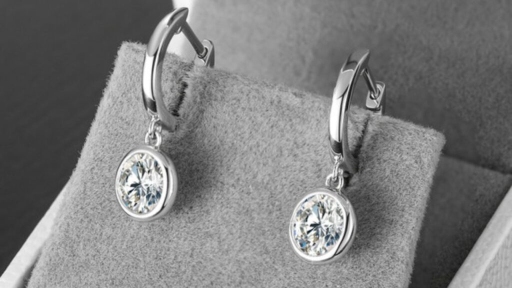 A pair of elegant diamond drop earrings showcased in a soft gray jewelry box.