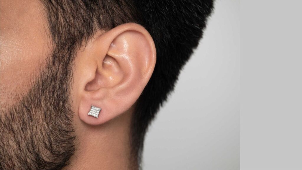 A man sporting a pair of elegant diamond stud earrings, adding a touch of sophistication to his look.