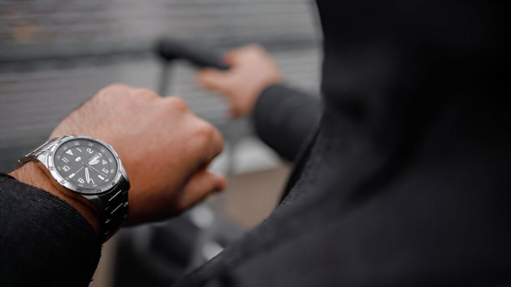 A man checks the time on his silver watch with a black band.