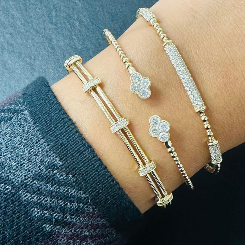 A stylish arm adorned with three elegant gold bracelets, each featuring sparkling diamonds and unique designs.